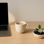 Minimalistischer Schreibtisch mit Laptop, Kaffeetasse und einer Schale mit frischen Aronia-Beeren – Symbol für Dank und Ruhe nach erfolgreicher Anmeldung